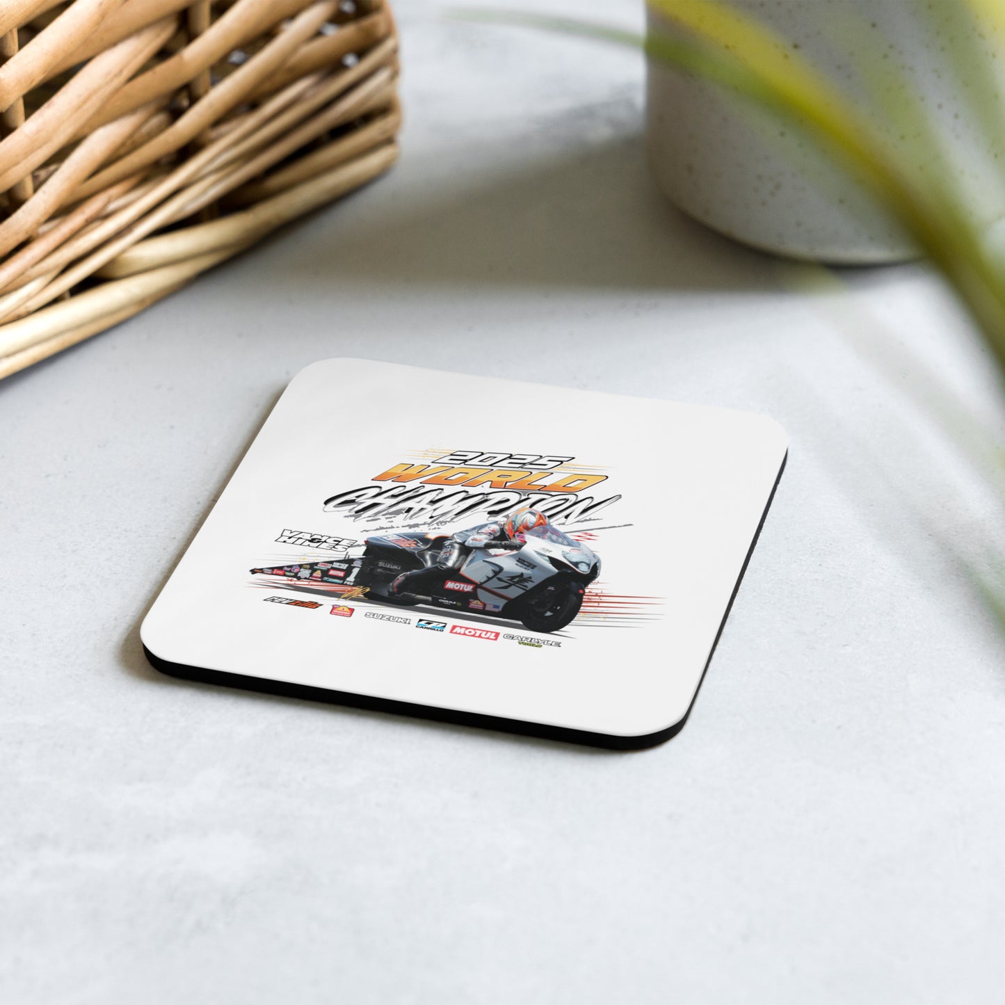 White-top cork-back coaster with racing motorcycle graphic on a light surface